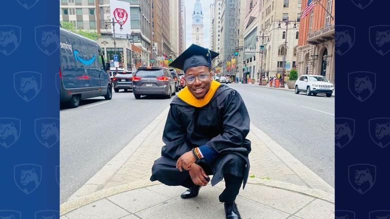 Man in cap 和 gown crouching near City Hall in Philadelphia